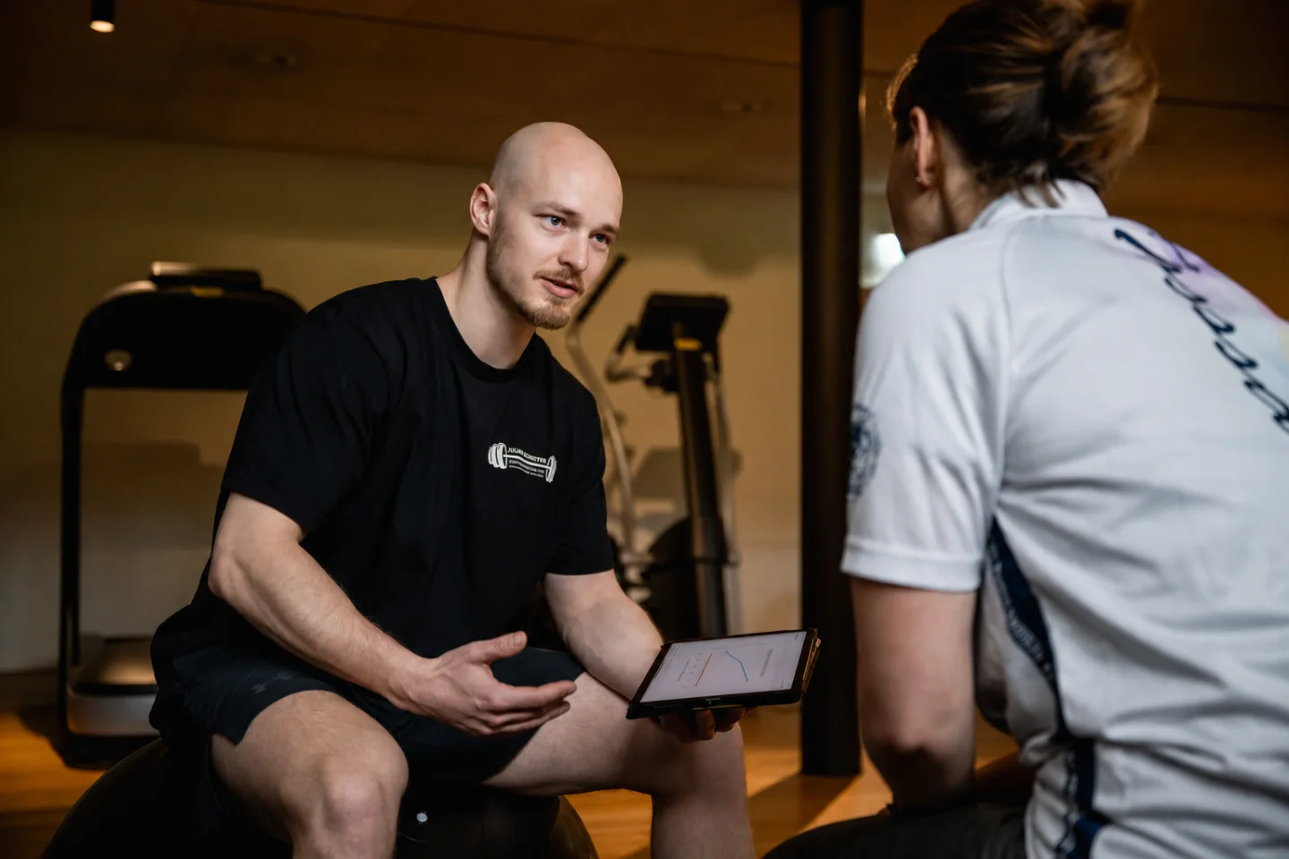 Julian Schuster erklärt einer Kundin die Trainingsplanung